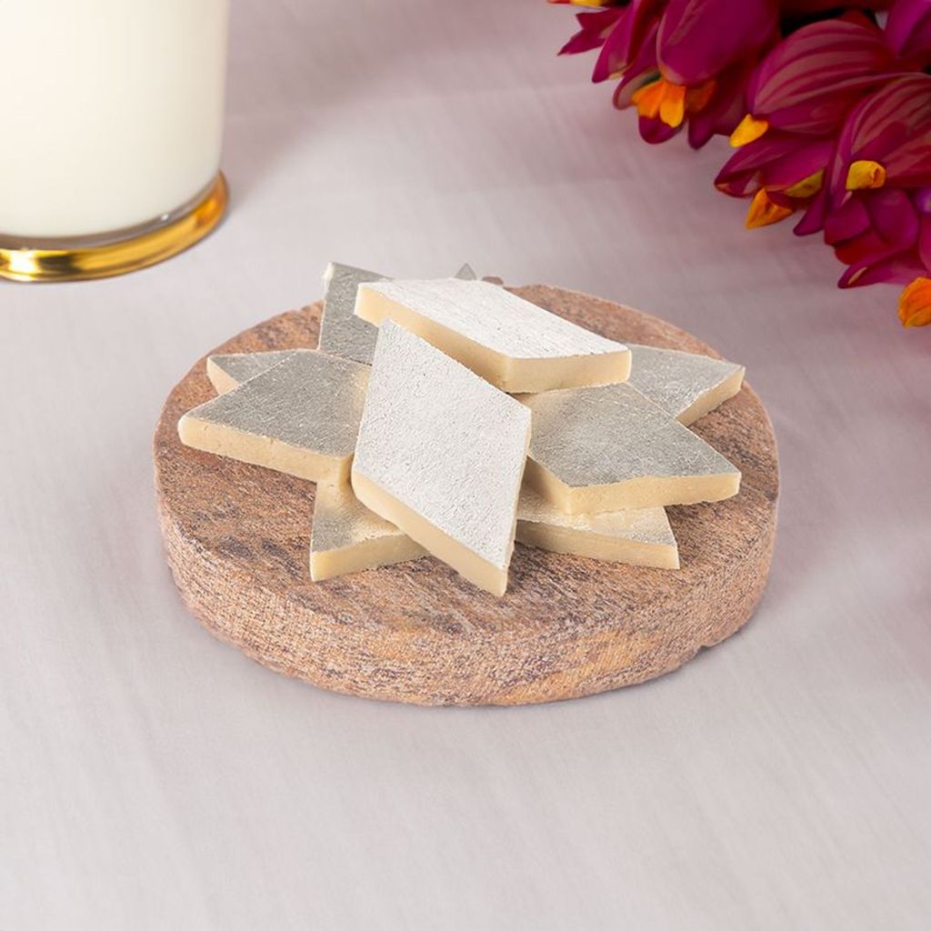 indian sweet kaju katli served on a round wooden board