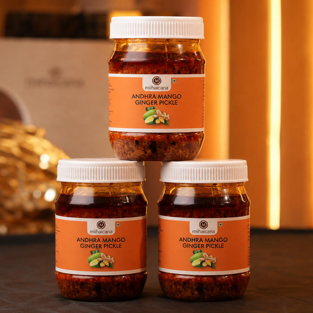 Three jars of Andhra Mango Ginger Pickle on a dark surface with a blurred decorative background.