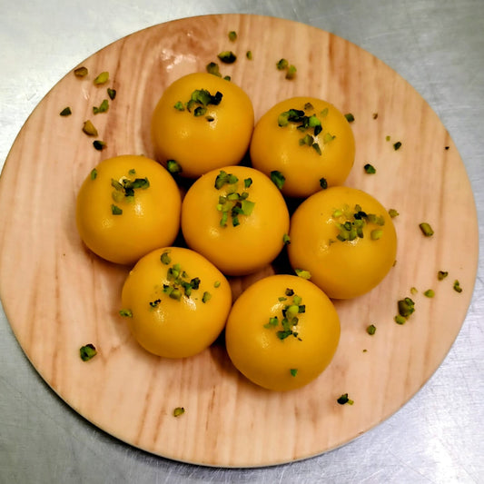 Yellow spherical food items garnished with green herbs on a wooden board.