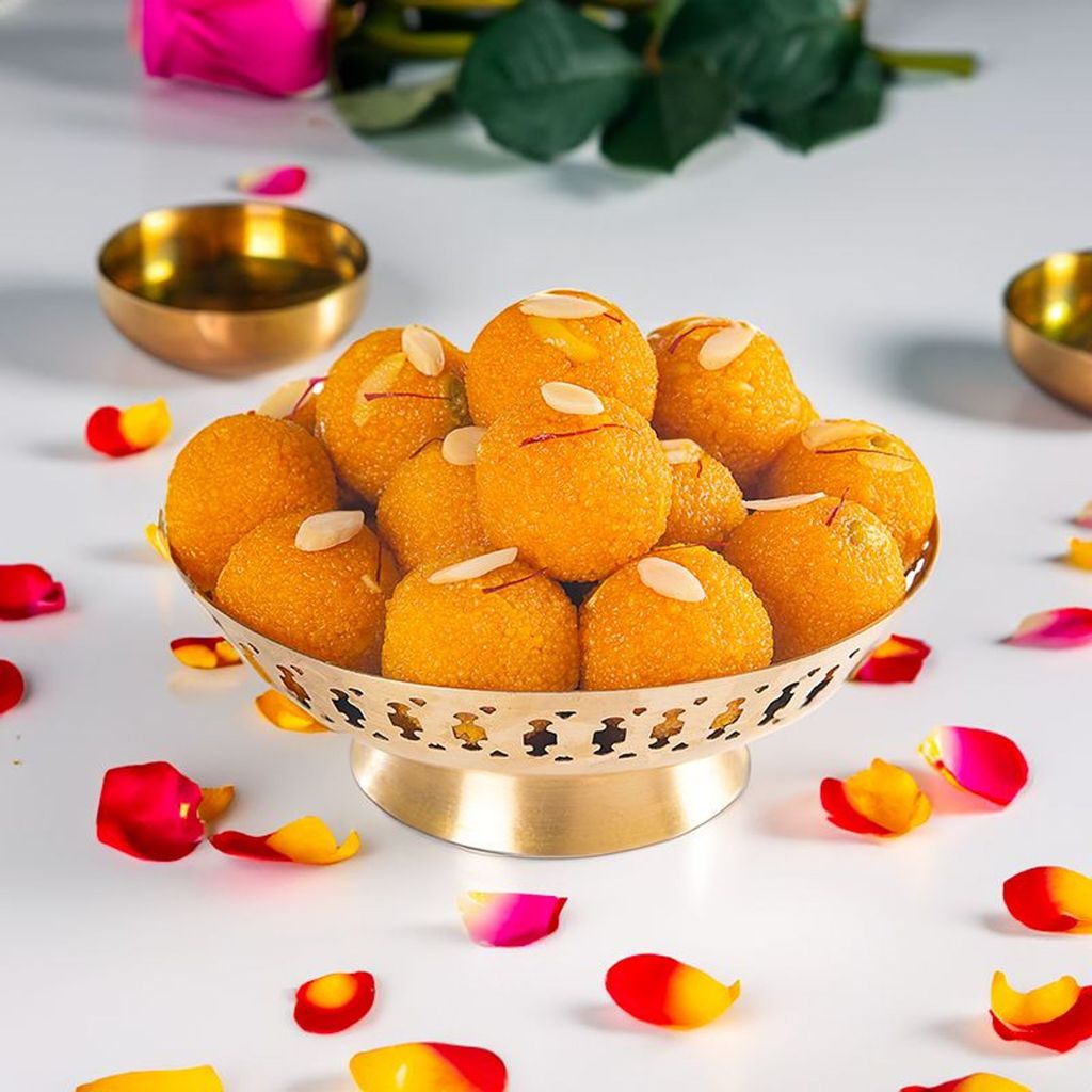 motichur laddu garnished with almonds and saffron placed in a brass platter with rose petals