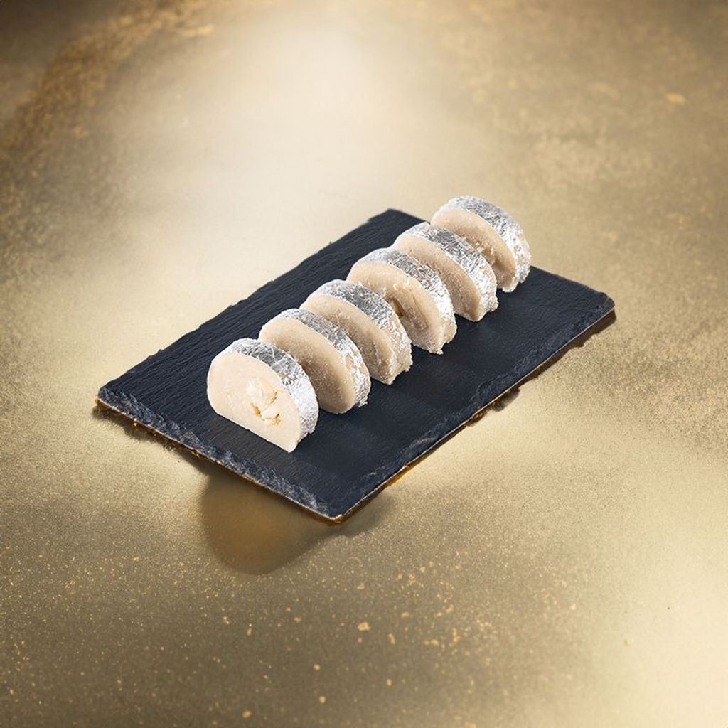 kaju crunch rolls wrapped in silver foil on a black stone plate