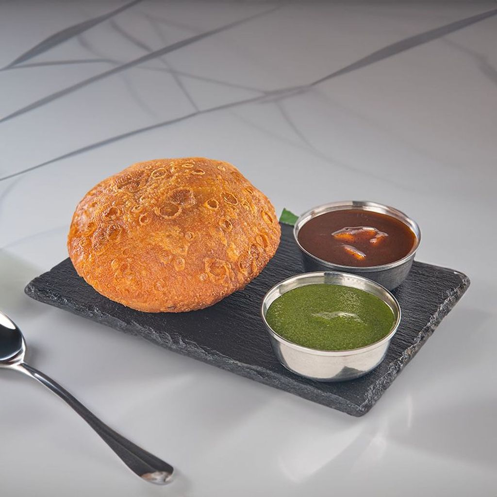 pyaaz kachori served on a black stone plate with chutneys.