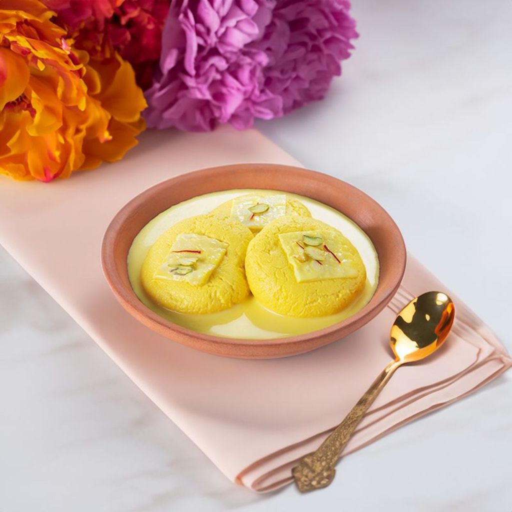 kesar rasmalai in a bowl of creamy milk with saffron strands and pistachio garnish