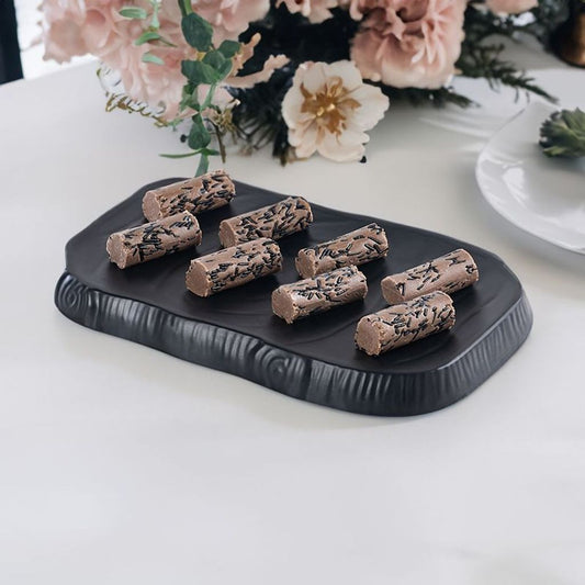 A close-up image of Mithaicana's Chocolate Rolls, showcasing their glossy, chocolatey exterior and cylindrical shape, garnished with finely chopped pistachios and a touch of edible silver leaf