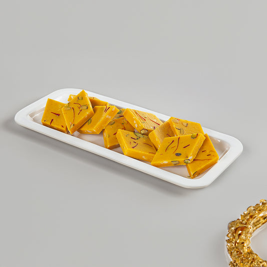 Yellow square-shaped candies on a white rectangular plate with a gray background