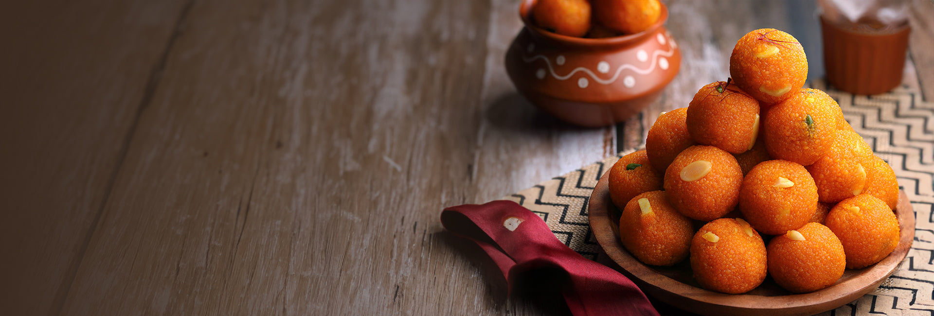 motichoor laddoos stacked on a decorative wooden platter.