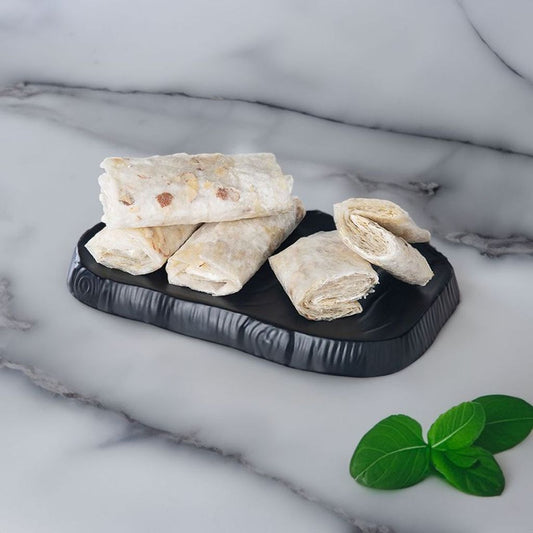 Rolled-up items on a black marble tray with green leaves on a marble surface