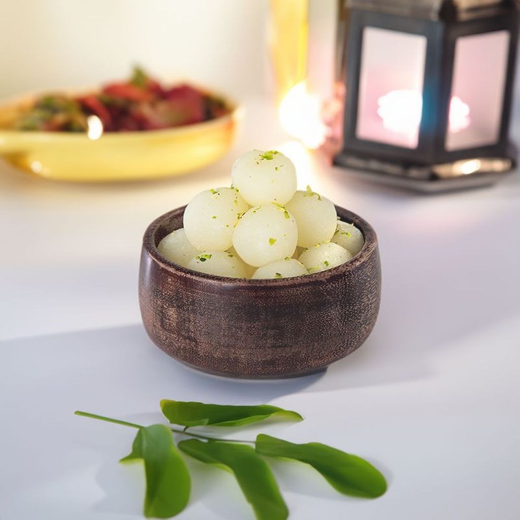 angoori rasgulla with pistachio garnish in a wooden bowl